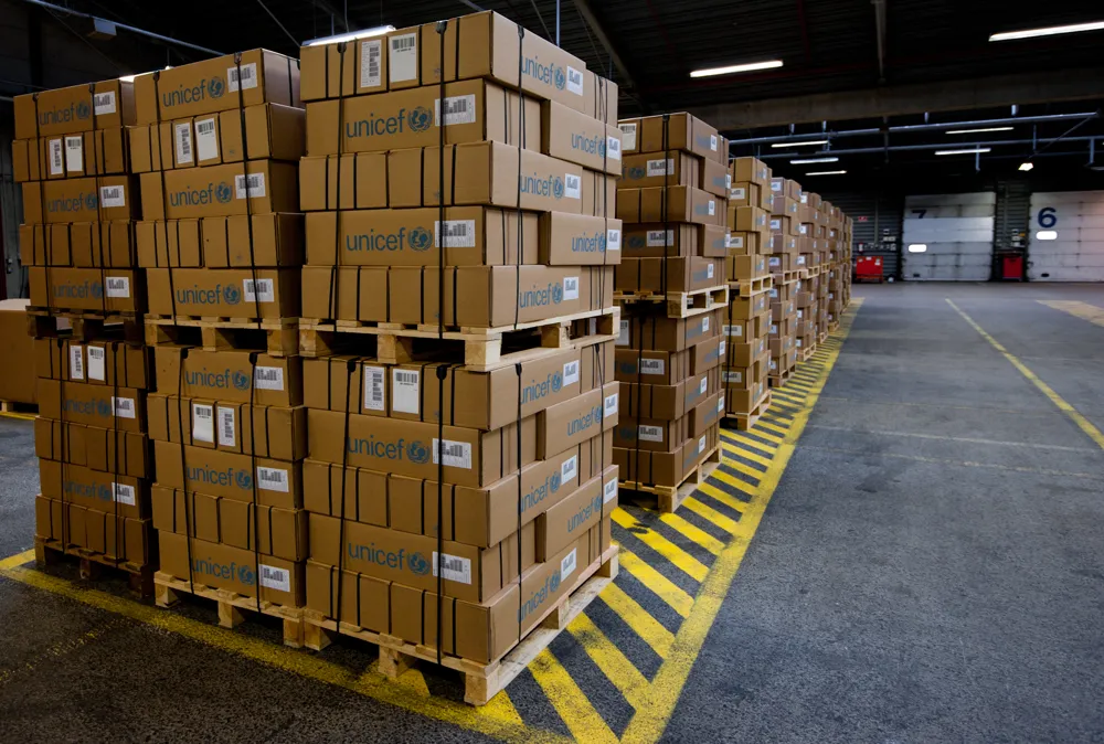 Rows of pallets loaded with stacked cardboard cases in a warehouse aisle.