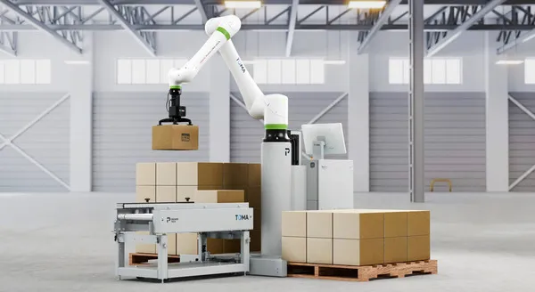 A white FANUC cobot on a pedestal lifting a box between two pallets, with an infeed conveyor and touch screen.