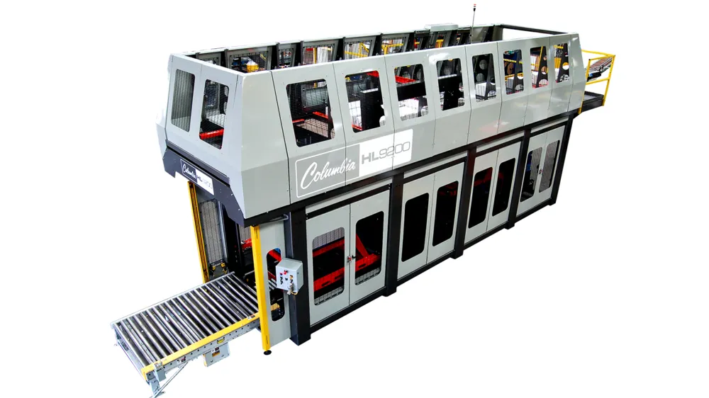 A long enclosed in-line palletizer with windows along its side and a roller conveyor at the discharge end.